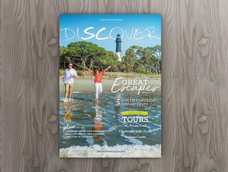 The cover of Discover South Carolina Magazine featuring a man and a woman on the beach in front of Hunting Island Lighthouse